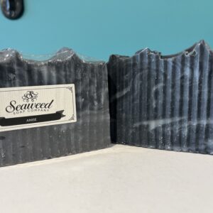 Two bars of ridged black seaweed soap under a blue sky.